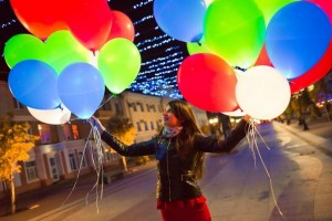 Разноцветные светящиеся шары с гелием в руках девушки во время прогулки по вечернему городу, купить в Букет шаров Измайлово.